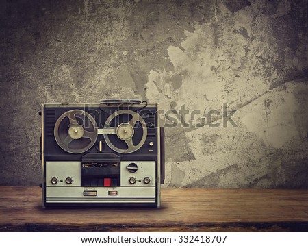 dirty old reel tape recorder on the wooden table. Retro toned