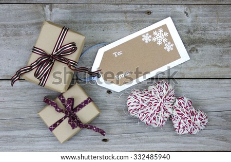Brown paper packages tied in ribbon by To From tag and rope hearts on antique rustic wooden background; above view