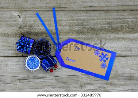 To From gift tag by royal blue Christmas decorations on antique rustic wooden background; above view