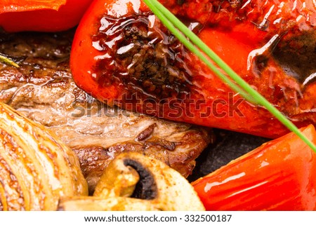 Mexican beef steak with grilled onions and red paprika on grill metal pan. Decorated with fresh herbs. Macro. Photo can be used as a whole background.