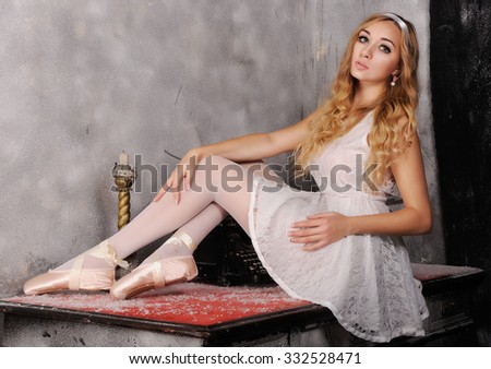 Portrait of beautiful ballerina which posing against dark background with typewriter