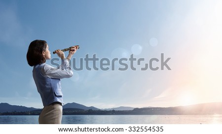 Young businesswoman looking in spyglass on sunrise at horizon Royalty-Free Stock Photo #332554535