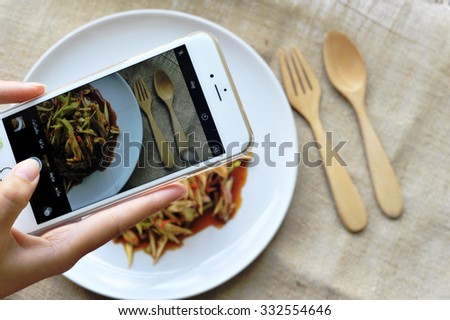 Close up view of life-view process of smart phone for taking a picture of spicy mango salad in home cooking.