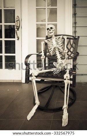 Skeleton ghost sit on a chair. Human skull waiting someone in Halloween day.