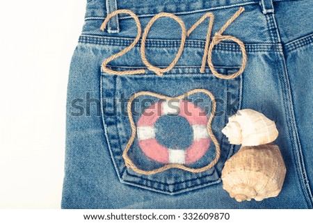 Lifebuoy, rope number 2016 and seashell on jeans pocket background. Toned.