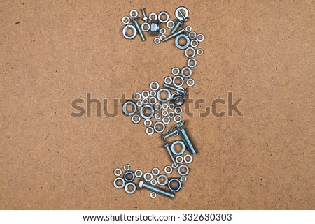 Three from bolts and nuts. Photo of mozaic sign on wood background.