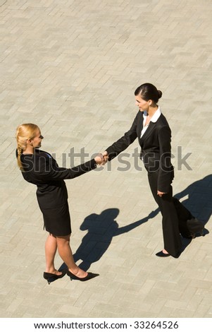 Photo of two female partners handshaking outdoor