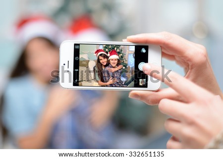 people, man and woman in love taking pictures, pictures of them on the phone in the background, near, Christmas tree, christmas party, happy new year 2016. taking selfie with a smart phone