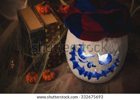 White halloween pumpkin head in clown hat with burning candles . Halloween holidays art design, celebration.