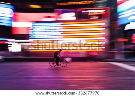 picture with camera made motion blur effect of a bicycle rider in front of US flag at Times Square, NYC