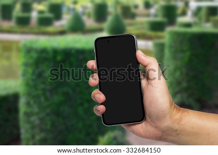 Closeup image with male hand hold and touch screen smart phone, tablet,cellphone over blurred Central Suburban background.