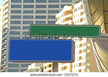 one green and one blue empty street signs, buildings in background