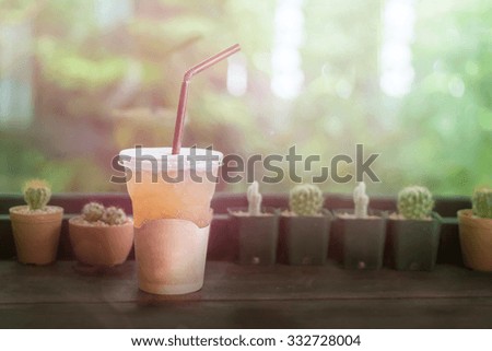 take-home cup of ice coffee on wooden table, vintage background.