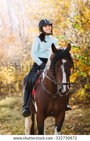 Happy Young woman riding a brown horse Royalty-Free Stock Photo #332730872