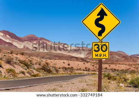 Yellow sign with curved arrow and road, California
