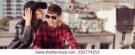 Panorama of fashionable girl kissing her handsome boyfriend outdoors
