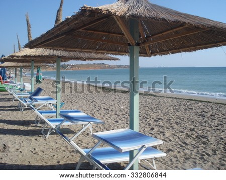 Row of thatched umbrellas and loungers on beach in the morning, in Vama Veche resort at the Black Sea in Romania