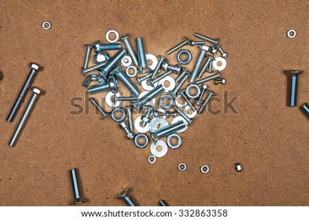 Bright heart from bolts and nuts. Photo of mozaic sign on wood background.