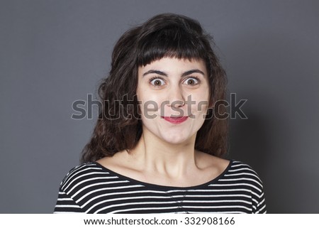 satisfaction and smile concept - cheeky young brunette smiling with eyes wide open expressing joy and excitement with her face