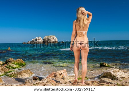 Smiling woman in swimsuit standing on beach, sunny summer day
