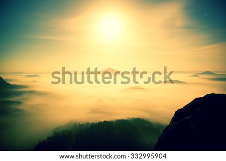 Full moon night with sunrise in a beautiful mountain of Bohemian-Saxony Switzerland. Sandstone peaks and hills increased from foggy background