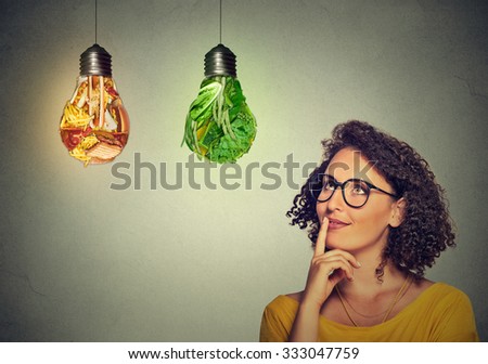 Portrait beautiful woman thinking looking up at junk food and green vegetables shaped as light bulb isolated on gray background. Diet choice right nutrition healthy lifestyle wellness concept Royalty-Free Stock Photo #333047759