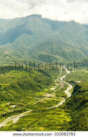 A breathtaking aerial view of the winding Amazon River cutting through the lush green Andes mountains in Ecuador.