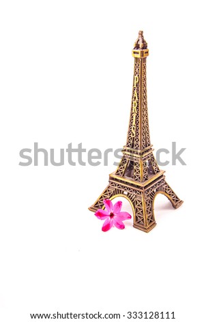 Model of little Eiffel Tower with a pink flower isolated on white. Symbol of Paris and travel in France.