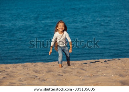 Adorable happy smiling little girl on beach vacation. jeans