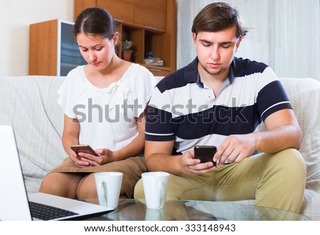 Young spouses burying in smartphones instead of talking indoors
 Royalty-Free Stock Photo #333148943