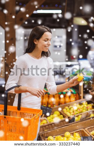 sale, shopping, consumerism and people concept - happy young woman with food basket in market with snow effect