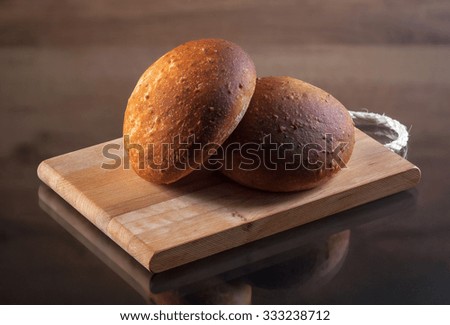 Fresh baked bread on bread board with wooden texture and wooden background