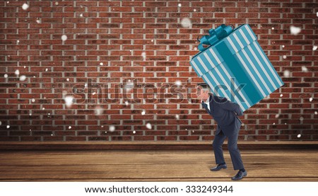 Stylish man with giant gift against room with brick wall