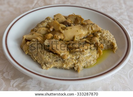 in the picture typical italian food ,Polenta Taragna and mushrooms (Porcini) on white dish at restaurant.