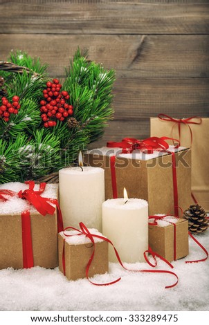 Christmas decoration with burning candles, gift boxes and christmas tree branches. Vintage style toned picture