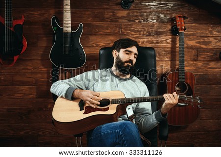 man playing guitar. Guitars on wall on background, love music concept