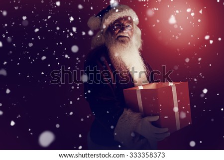 Father christmas holding a gift against snow