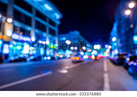Nights lights of the big city, night avenue in the light of lanterns and illuminated shop windows. Wide-angle view, defocused image, im blue tones