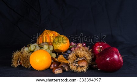Group of autumnal fruits and vegetables on a black background.