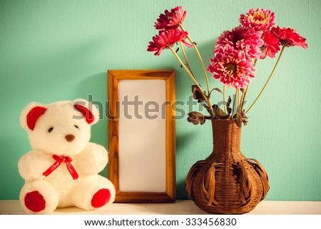 Teddy bear,picture frame,flower in vase on white,green wood background.