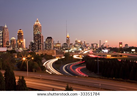 Atlanta skyline just before sunset showing downtown buildings, roads and traffic streaks.