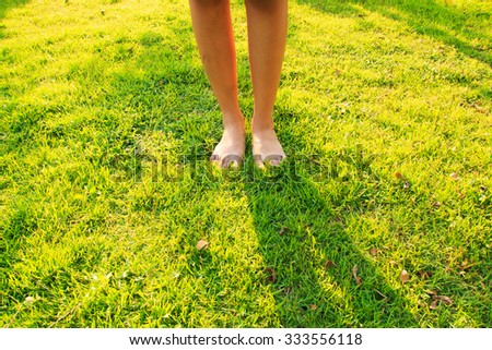 Woman feet on the green grass in morning
