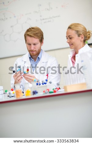 
Professor and his assistant studying molecular model in chemical cabinet  