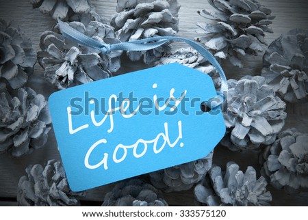 One Light Blue Label On Fir Cones And White Wooden Background. English Life Quote Life Is Good Vintage Or Retro Style Used As Winter Or Christmas Background With Frame