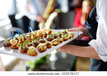 Waiter carrying plates with meat dish on some festive event, party or wedding reception Royalty-Free Stock Photo #333578117