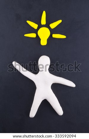 A man from clay on the black background with Idea lamp bulb symbol.