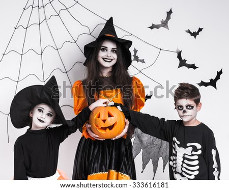 Children in costumes celebrating Halloween, against the background of bats and cobwebs