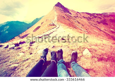 Tourism in mountains. A couple of tourists rest on the mountain path. Nature in mountains at autumn. Instagram vintage picture.