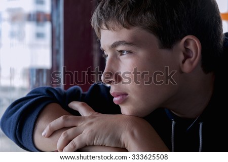Pensive child looking through a window Royalty-Free Stock Photo #333625508