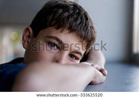 Pensive child looking through a window Royalty-Free Stock Photo #333625520